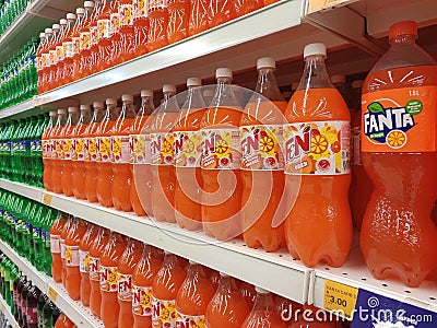 Soft drinks or carbonated drinks arranged and stacked on the rack inside the huge supermarket for sale. Sorted by the brand to mak Editorial Stock Photo