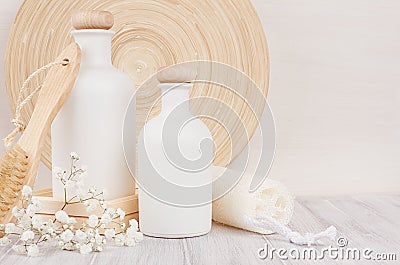 Soft elegant bathroom decor of white cosmetics bottles with comb, flowers on white wood board, mock up, copy space. Stock Photo