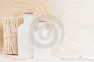 Soft elegant home decor with white bottles and beige twigs on white wooden board. Stock Photo