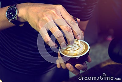 Soft focus at Barista performing skill of pouring latte art in wing tulip pattern by using handleless pitcher. Selective focus on Stock Photo