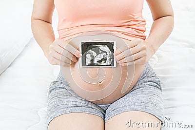 Soft focus and blurry of happy pregnant woman lying on bed at home holding and showing ultrasound scan photos. Pregnancy, Fetal Stock Photo