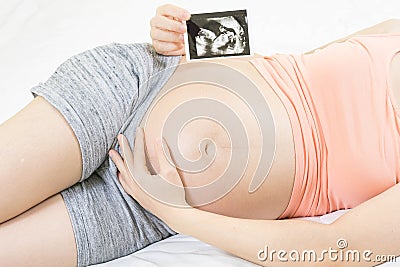 Soft focus and blurry of happy pregnant woman lying on bed at home holding and showing ultrasound scan photos. Pregnancy, Fetal Stock Photo