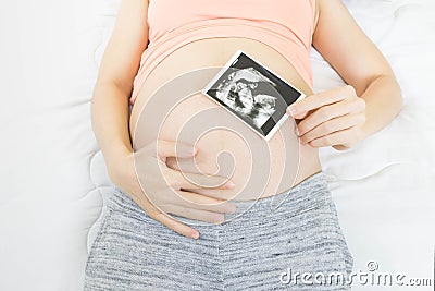 Soft focus and blurry of happy pregnant woman lying on bed at home holding and showing ultrasound scan photos. Pregnancy, Fetal Stock Photo