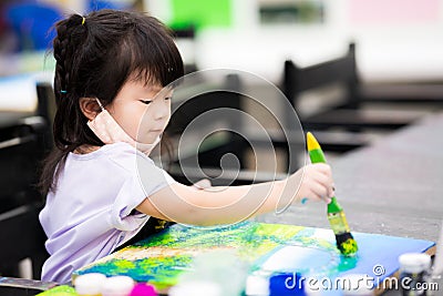 Girl stood on escalator. Child wave their hands to the camera. Kid wearing cloth mask in shopping mall. Children hand in hand with Stock Photo