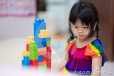 Soft focus. Girl play with colorful plastic blocks. Child play alone. Children play house activities. Stock Photo