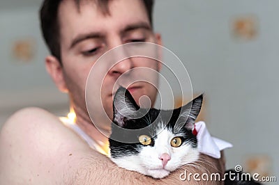 hansome man holding and looking at cute black and white cat with yellow eyes Stock Photo