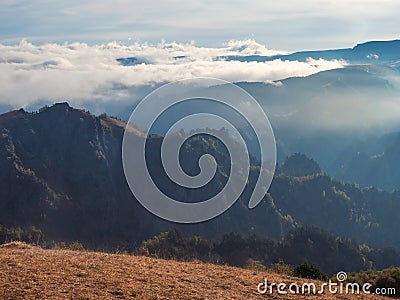 Soft focus. Mountains in a dense fog and sunny slope. Mystical landscape with beautiful sharp rocks in low clouds. Beautiful Stock Photo