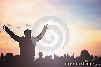 Praise and worship concept: Silhouette human raising hands to praying God on blurred cross with crown of throne sunset background Stock Photo