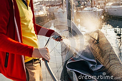 Man washes folded sail on boat or yacht in port Stock Photo