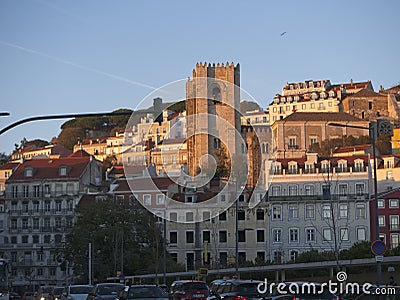 Soft glowing golden light from sunset enhances Alfama neighborhood in Lisbon Portugal as seen from the shores of the Tagus River. Editorial Stock Photo