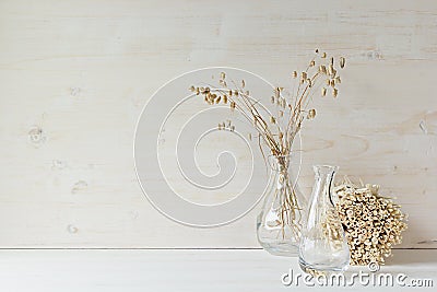 Soft home decor of glass vase with spikelets and stalks on white wood background. Stock Photo