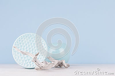 Soft light blue pastel color in minimalist home decoration - sphere ceramic vase, dish and old shabby tree on white wood board. Stock Photo