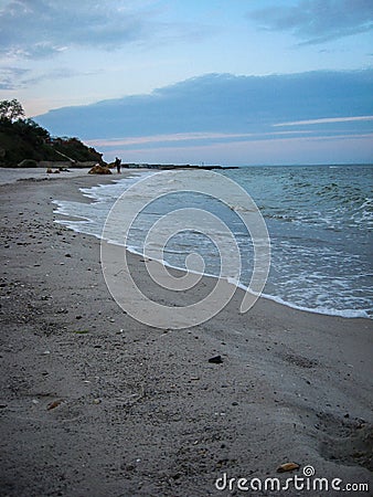 The soft sea waves gently roll on the sandy beach. Beautiful picture of dawn on the seashore Stock Photo