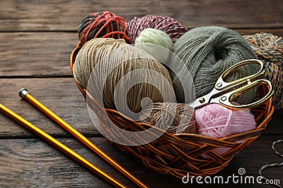 Soft woolen yarns, knitting needles and scissors on wooden table Stock Photo