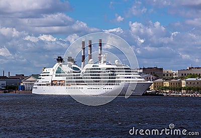 Soften edge envelope size view of large white colored ocean ship in Neva river of Saint Petersburg under blue summer cloudy sky Stock Photo