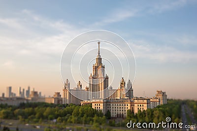 Soften edge view of sunset Moscow university framed with green trees under cloudy sky Stock Photo