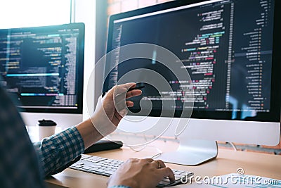 Software developer holds the pen pointing to the computer screen and is analyzing the code Stock Photo
