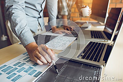 Software developer is pointing to the paper working and analyzing together the code written into the program on the computer Stock Photo