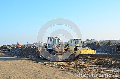 Soil Compactor and wheel loader at construction site. Vibration single-cylinder road roller leveling the ground for the construct Stock Photo