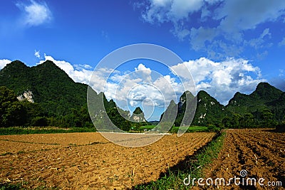 Soil on rice field after harvesting season with mountain and blue sky in Vietnam Stock Photo