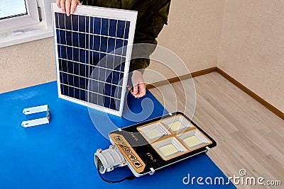 Solar panel for LED outdoor lighting, assembler mounts street light to bracket. Stock Photo