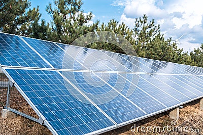 Solar panel over a blue sky and green trees. ecological alternative energy production Stock Photo