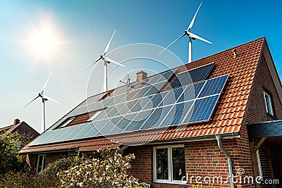 Solar panel on a roof of a house and wind turbins arround Stock Photo