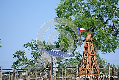 Solar Water well with Texas Windmill in front of summer green trees, farm ranch fence and blue sky background Stock Photo