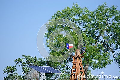 Solar Water well with Texas Windmill in front of summer green trees, farm ranch fence and blue sky background Stock Photo