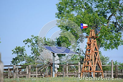 Solar Water well with Texas Windmill in front of summer green trees, farm ranch fence and blue sky background Stock Photo
