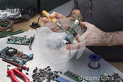 Solder soldering solder integrated circuit. Hand of a soldering soldier with soldering iron. Stock Photo