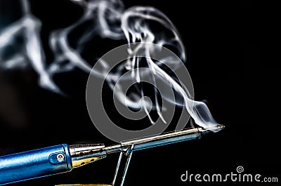 soldering iron with smoke on a black background. Electrical Stock Photo