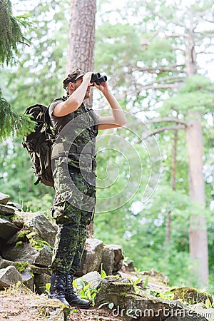 Soldier with binocular and backpack in forest Stock Photo