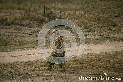 Soldier in camouflaged sniper suit searching position Stock Photo