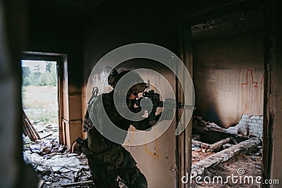 Soldier in full US MARSOC equipment entering abandoned building, aiming different angles with MK18 assault rifle Stock Photo