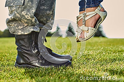 Soldier in leather boots and girl in sandals. Stock Photo