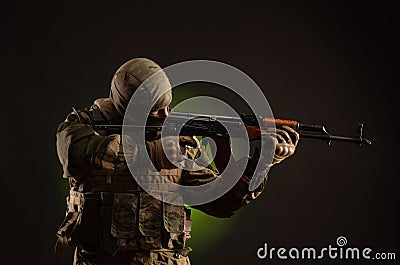 Soldier militia saboteur in military clothing with a Kalashnikov rifle on a dark background Stock Photo