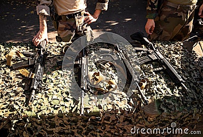 Soldier silhouettes near multiple semi-automatic rifles Editorial Stock Photo