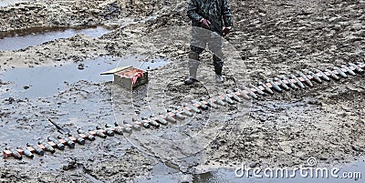 Soldier Preparing Weapons in a Muddy Field During Intense Warfare and Conflict Stock Photo