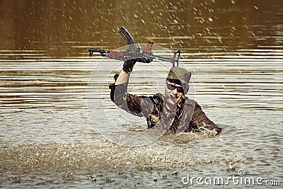 Soldier in uniform swimming in lake with assault rifle Stock Photo