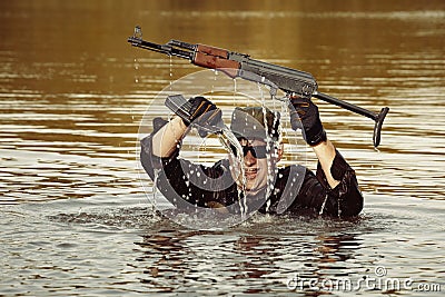 Soldier in uniform swimming in lake with assault rifle Stock Photo