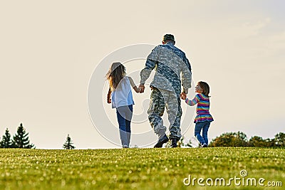 Soldier walking with little girls holding hands. Stock Photo