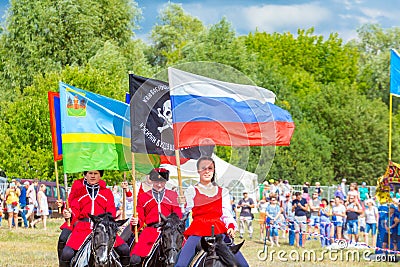 Solemn entry of a group of horse racing with flags in the meadow of the festival Editorial Stock Photo