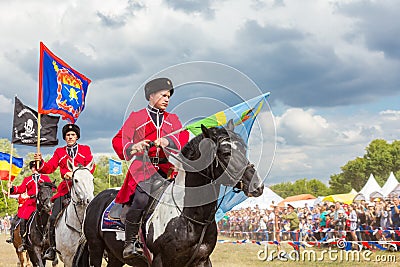 Solemn entry of a group of horse racing with flags in the meadow of the festival Editorial Stock Photo