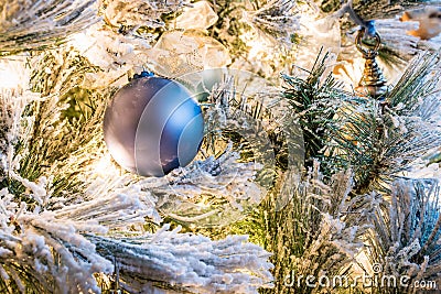 A solid blue Christmas ornament on a flocked Christmas tree Stock Photo