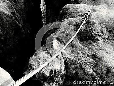 Solid knot on steel rope. Iron twisted rope fixed in block by screws snap hooks. Detail of rope end anchored into sandstone rock Stock Photo