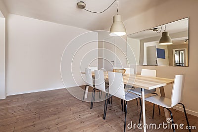 Solid wood dining table next to a mirror in an empty room with chestnut flooring Stock Photo