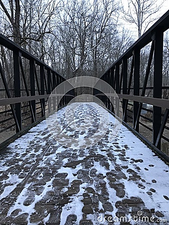 A SOLID WOODEN BRIDGE GUIDES HIKERS ALONG A SNOWY TRAIL IN A PUBLIC PARK Stock Photo