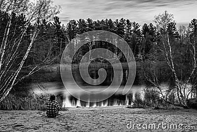 Solitary Contemplation: Long Exposure Monochrome Image of a Seated Man on a Sandy Beach Stock Photo