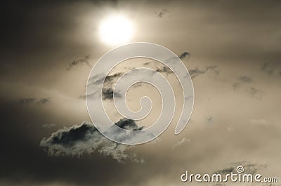 Solitary Puffs of Cloud Floating Past The Setting Sun Stock Photo